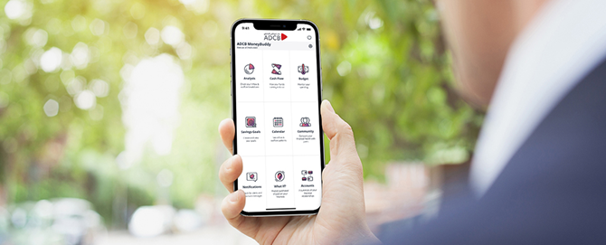 Person holding a smartphone displaying the ADCB mobile banking app