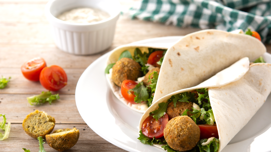 Falafel sandwich stuffed with fresh veggies and sauces in fresh bread.